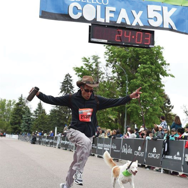 CORE employee, Chris Rodenburg, finishing the Colfax 5K with a dog next to him
