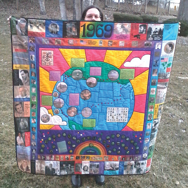 CORE employee, Heidi Row, posing with a quilt of items from the year 1969