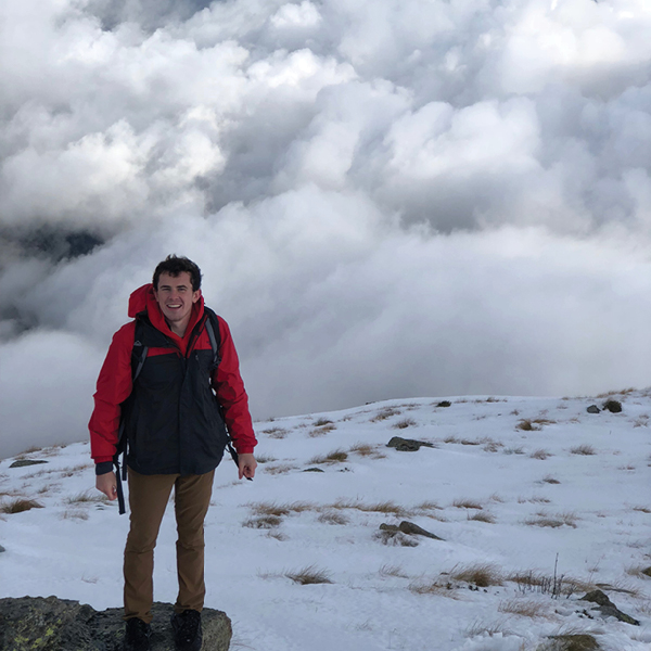 CORE employee Joseph Tynan hiking on a mountain surrounded by snow