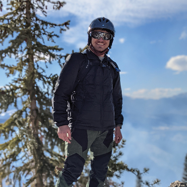 CORE employee Max Batanian, posing on top a mountain with a helmet on